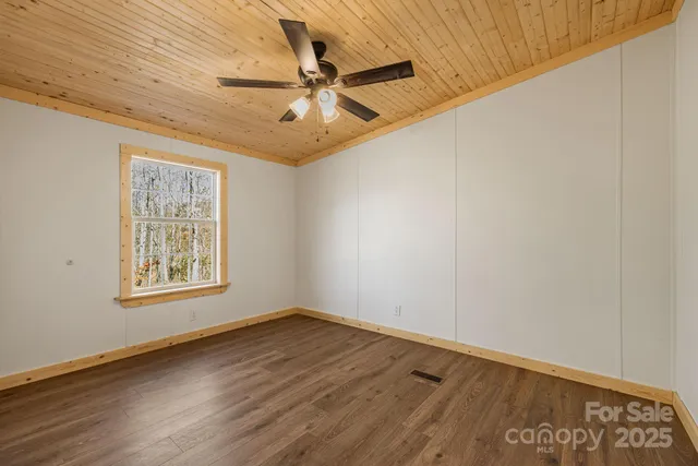 an empty room with wooden floor fan and windows