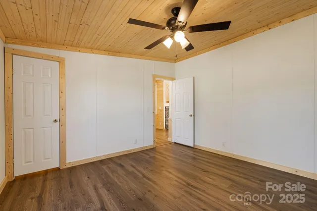 an empty room with wooden floor fan and windows