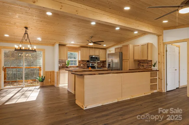 a kitchen with stainless steel appliances granite countertop a refrigerator a sink dishwasher a stove and a dining table with wooden floor