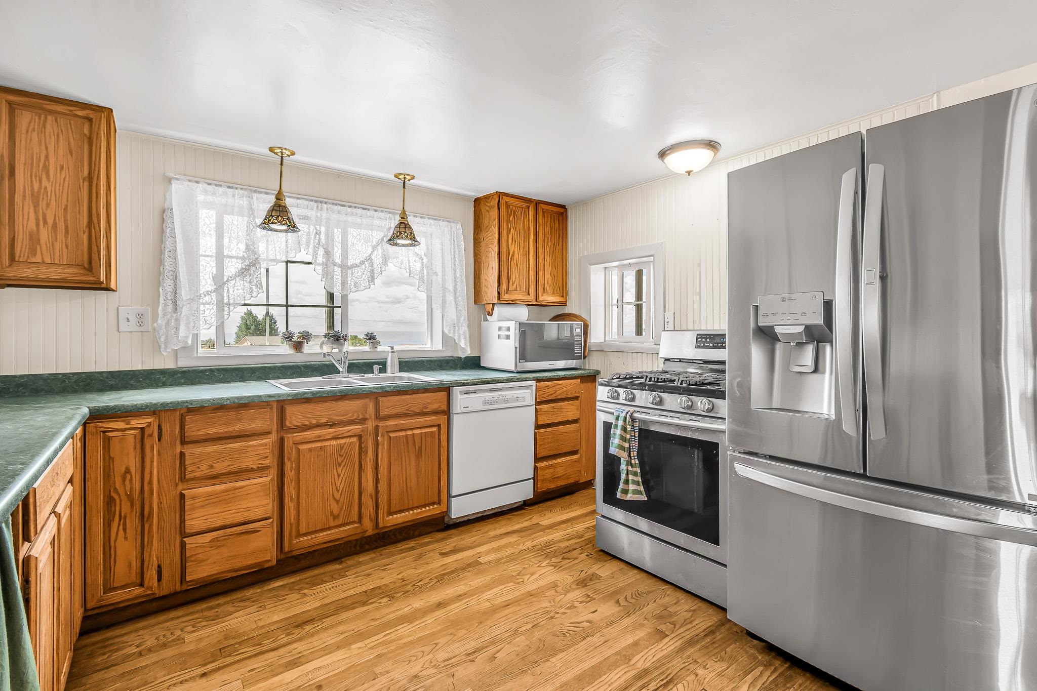 24413 Ute Trail Road Cedaredge, CO 81413 - Photo 7 of 40 a kitchen with stainless steel appliances granite countertop a refrigerator a sink dishwasher a stove with wooden cabinets and wooden floor