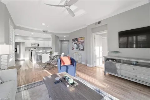 a living room with stainless steel appliances kitchen island granite countertop furniture and a wooden floor