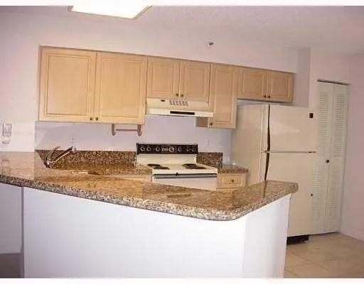 a kitchen with kitchen island granite countertop a refrigerator a stove a sink and white cabinets with wooden floor