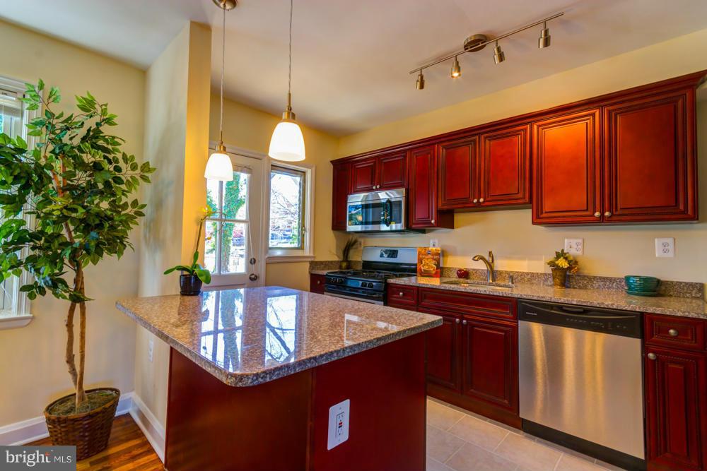 1027 Witherspoon Road Baltimore, MD 21212 - Photo 1 of 21 a kitchen with stainless steel appliances granite countertop a sink a stove and a wooden cabinets