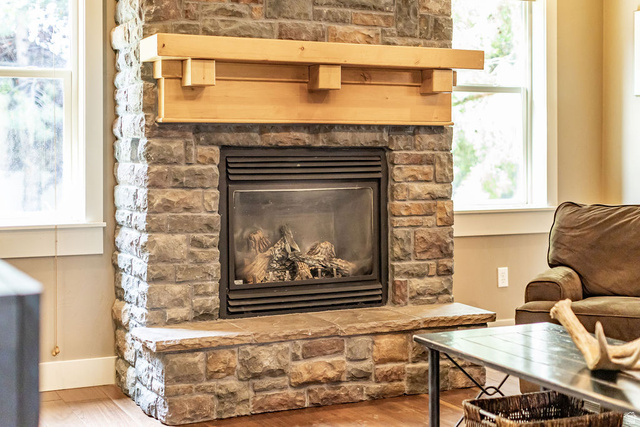 288 525 South Providence, UT 84332 - Photo 10 of 71 Stone-clad fireplace featuring a gas insert, a substantial wood mantel, a matching stone hearth, and wood-finish flooring