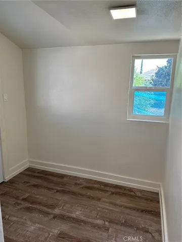 an empty room with wooden floor cabinet and window