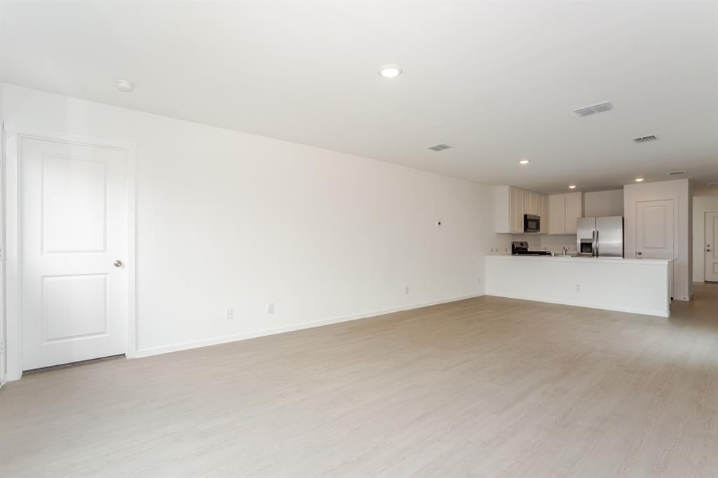 1419 Merlin Blf Street Forney, TX 75126 - Photo 5 of 24 Open-concept living space featuring light-colored flooring, recessed lighting, and a kitchen with white cabinetry, stainless steel appliances, and a breakfast bar