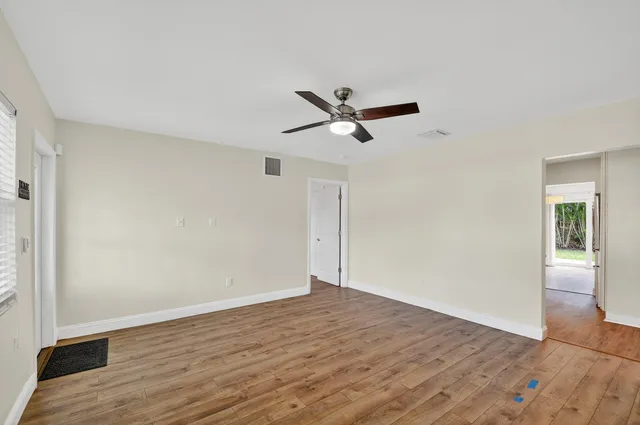an empty room with wooden floor and a ceiling fan