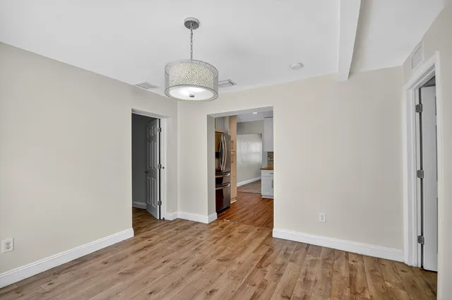 a view of a hallway with wooden floor and chandelier