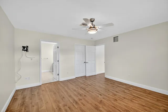 a view of empty room with wooden floor and ceiling fan