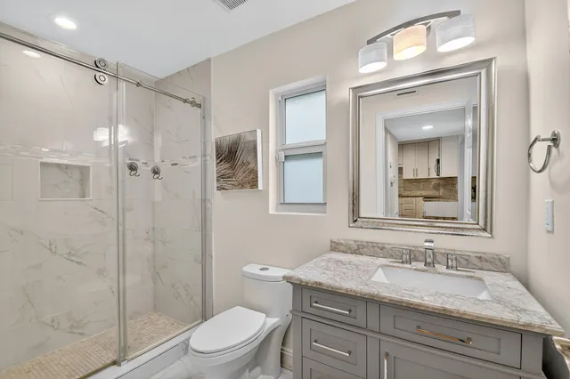 a bathroom with a granite countertop sink toilet a mirror and shower