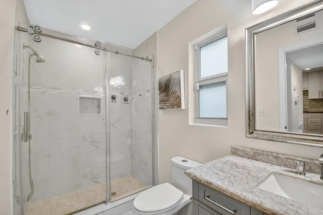 a bathroom with a granite countertop sink toilet and shower