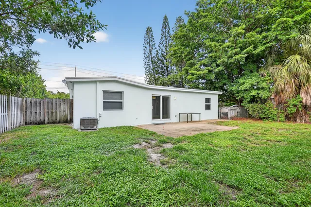 a view of a house with a yard and large trees