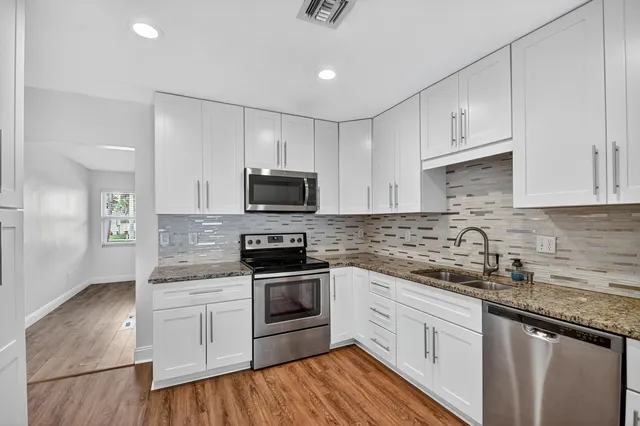 a kitchen with stainless steel appliances granite countertop a sink a stove a microwave and cabinets