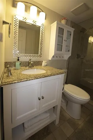 a bathroom with a granite countertop toilet sink and mirror