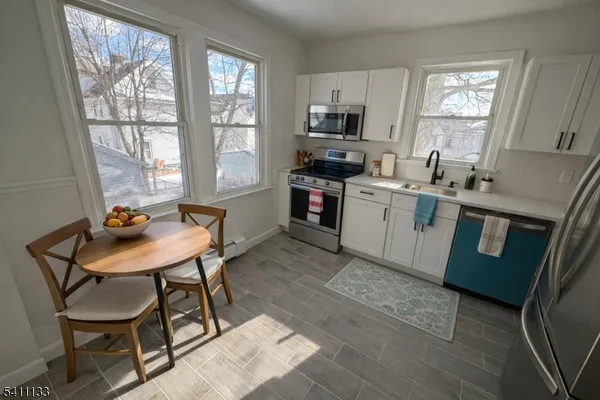 a kitchen with a stove a sink dishwasher a dining table and chair with wooden floor