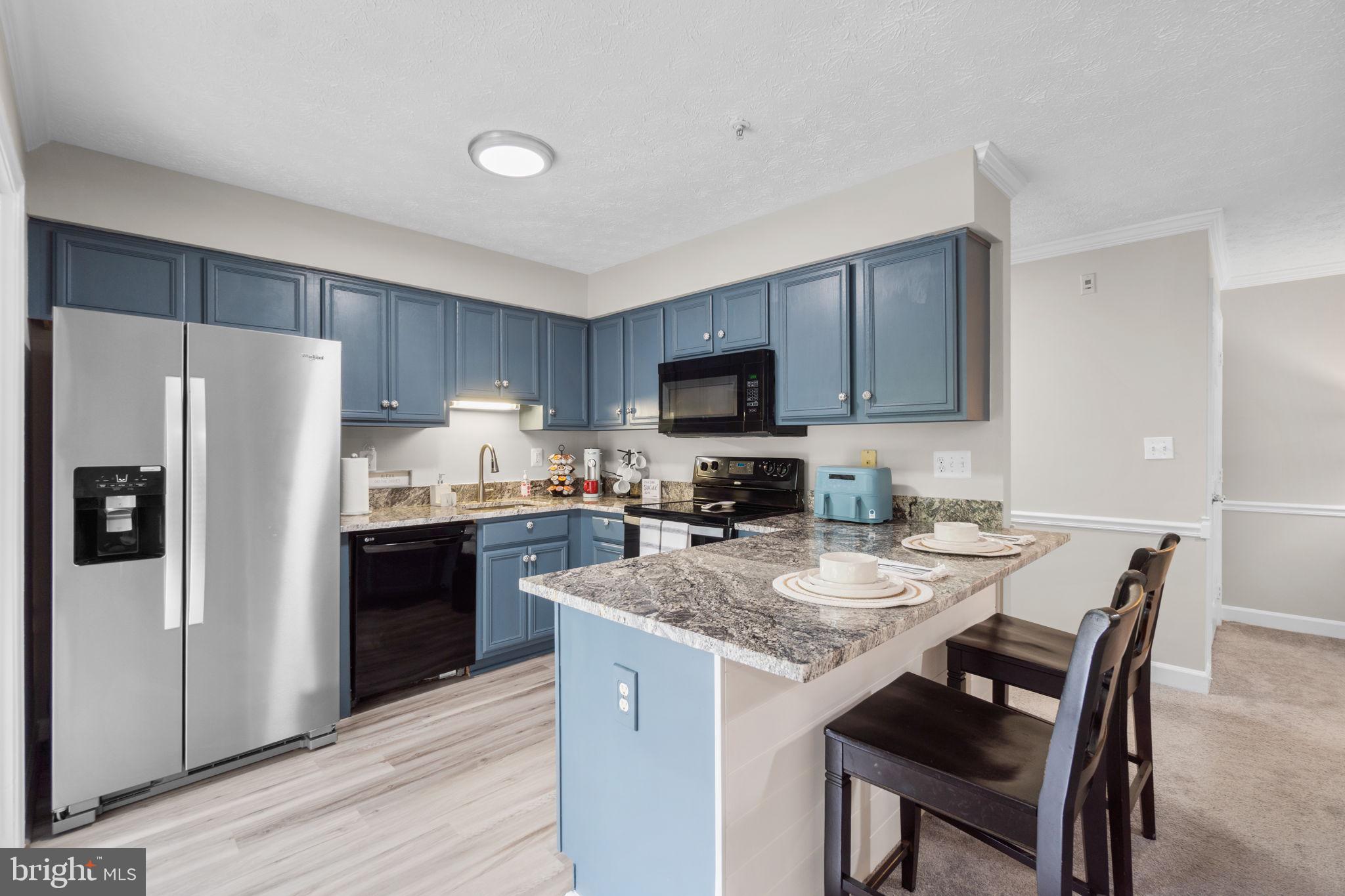6509 Springwater Court, Unit 6303 Frederick, MD 21701 - Photo 14 of 48 a kitchen with a refrigerator a stove top oven a sink dishwasher with a dining table and chairs