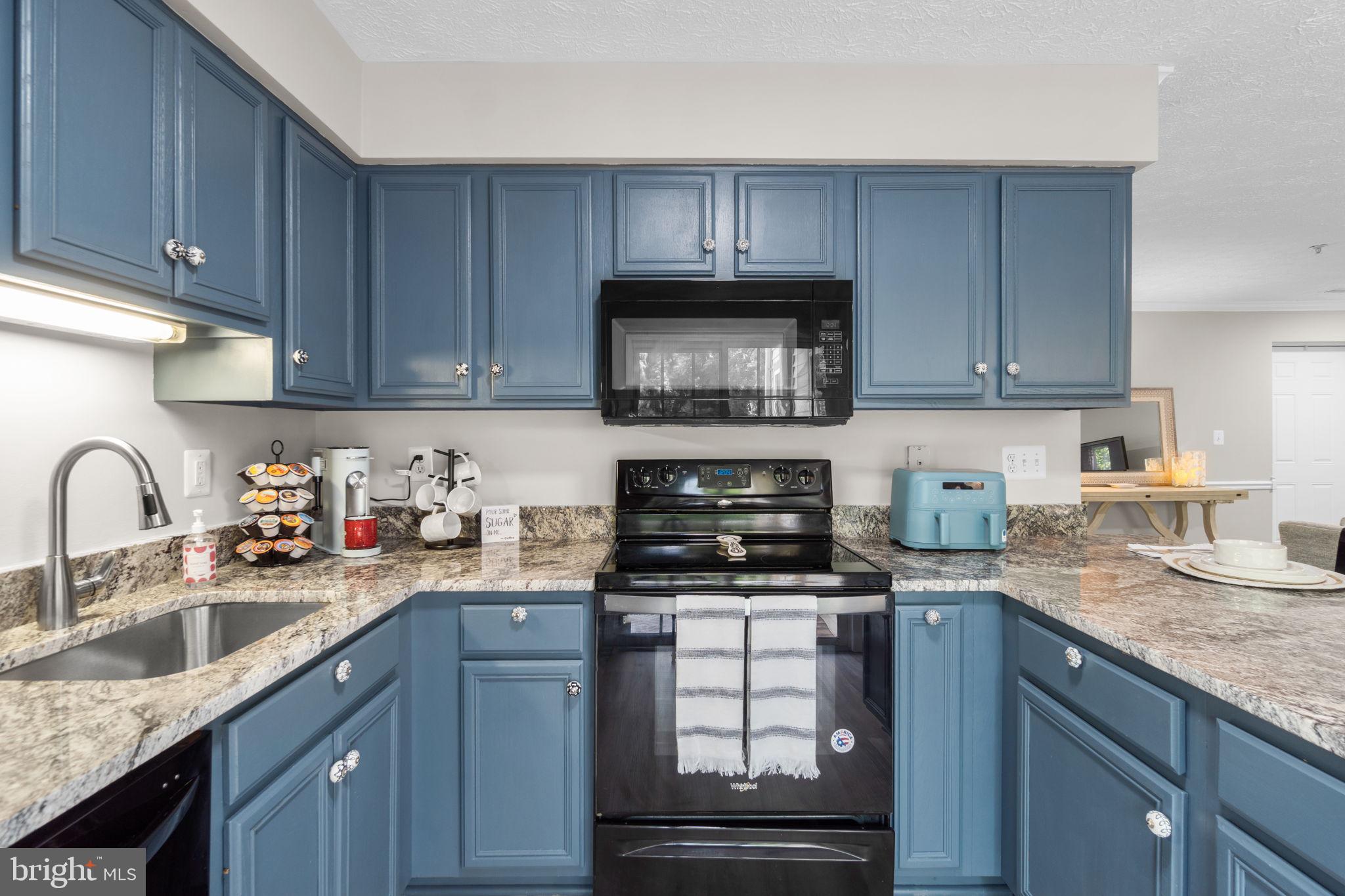 6509 Springwater Court, Unit 6303 Frederick, MD 21701 - Photo 16 of 48 a kitchen with granite countertop a sink a stove a microwave and cabinets