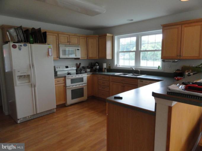 8235 Detour Road Denton, MD 21629 - Photo 5 of 30 a kitchen with a refrigerator a sink a stove a microwave and cabinets