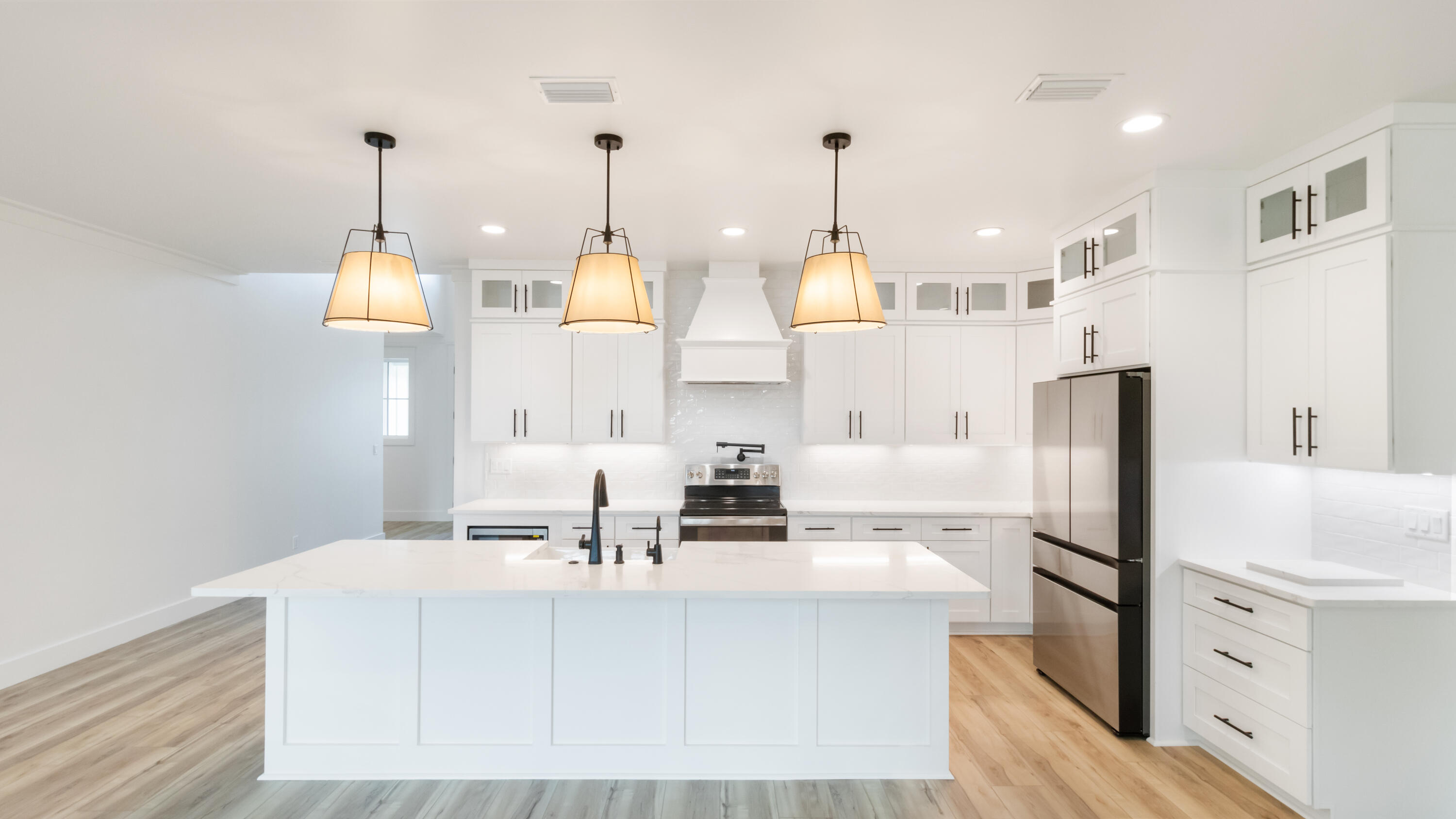 80 Muzzle Street Freeport, FL 32439 - Photo 48 of 71 a kitchen with stainless steel appliances kitchen island granite countertop a refrigerator a stove and white cabinets with wooden floor