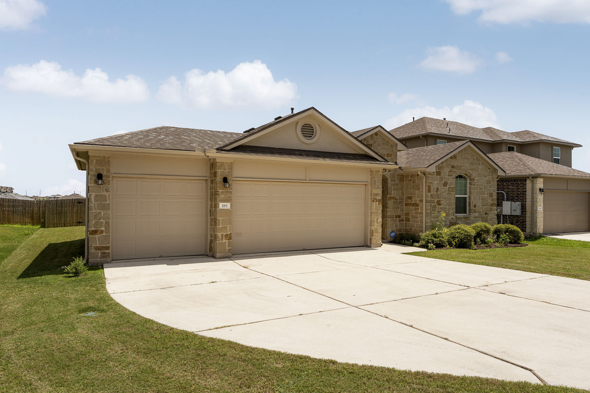 185 Struss Drive Georgetown, TX 78626 - Photo 2 of 23 A welcoming front exterior showcasing stone accents and a spacious driveway leading to a multi-car garage.