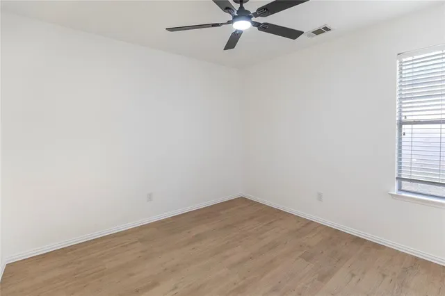 an empty room with a window and a fan