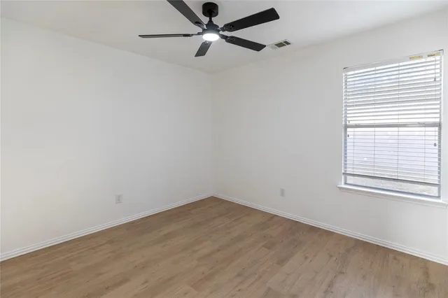 an empty room with a window and a fan