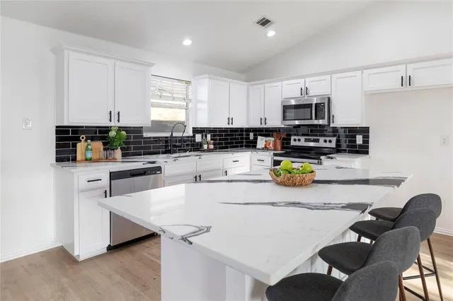 a kitchen with stainless steel appliances a sink a microwave a refrigerator and cabinets