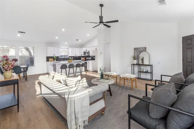 a living room with furniture kitchen view and a chandelier