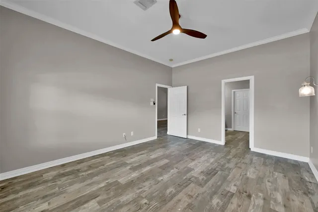 a view of an empty room with window and chandelier fan