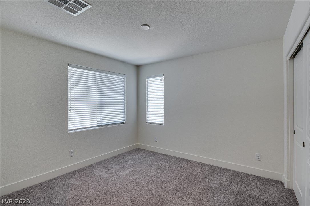 5954 Smith Valley Road Las Vegas, NV 89148 - Photo 20 of 23 A well-lit bedroom offering privacy and comfort, with plush carpet underfoot.