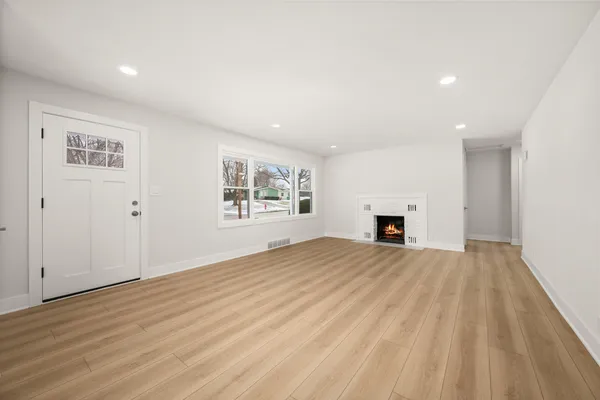 a view of empty room with wooden floor and fireplace