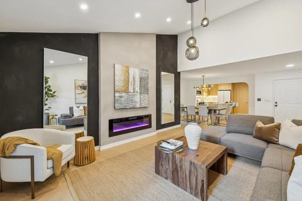 a living room with furniture kitchen view and a wooden floor