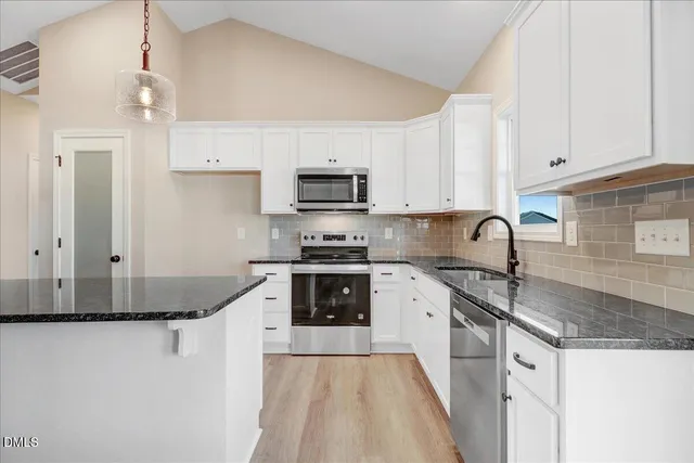 a kitchen with granite countertop a sink a stove and cabinets