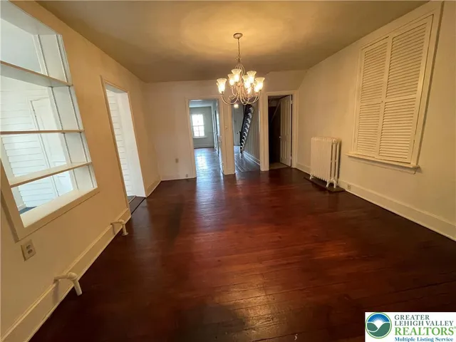 a view of a hallway with wooden floor and a chandelier
