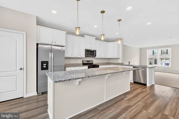a large kitchen with granite countertop a large counter top a sink stainless steel appliances and cabinets