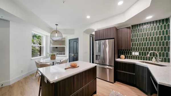 a kitchen with stainless steel appliances kitchen island granite countertop a sink refrigerator and cabinets