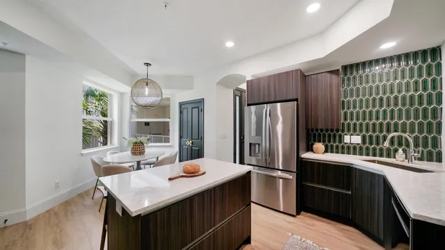 a kitchen with stainless steel appliances kitchen island granite countertop a sink refrigerator and cabinets