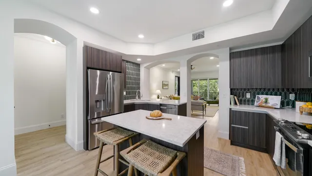 a kitchen with stainless steel appliances a dining table chairs and wooden floor