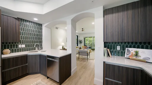 a kitchen with stainless steel appliances granite countertop a sink dishwasher stove and wooden cabinets with wooden floor