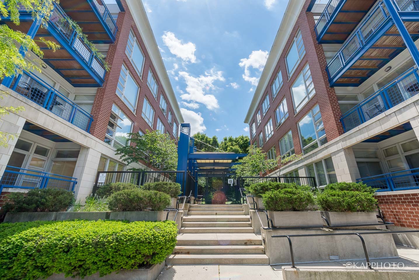 a front view of a multi story residential apartment building with yard and green space