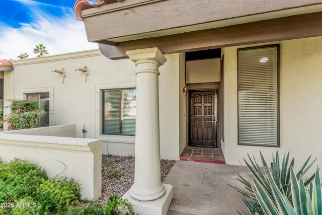 a front view of a house with a potted plant and floor to ceiling windows
