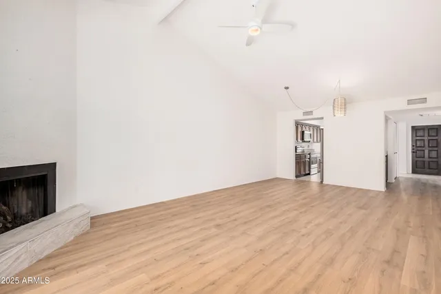 a view of empty room with wooden floor and fireplace