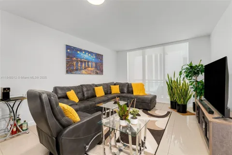 a living room with furniture a flat screen tv and a potted plant