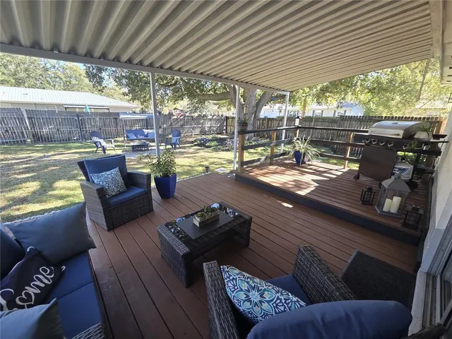 a view of a patio with couches chairs dining table and chairs barbeque grill with a small yard
