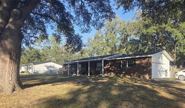 a view of a house with a yard and large tree