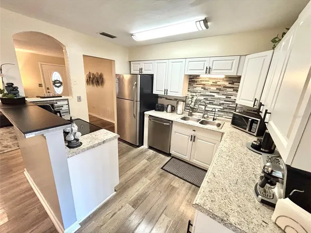 a kitchen with stainless steel appliances kitchen island granite countertop a refrigerator stove and sink