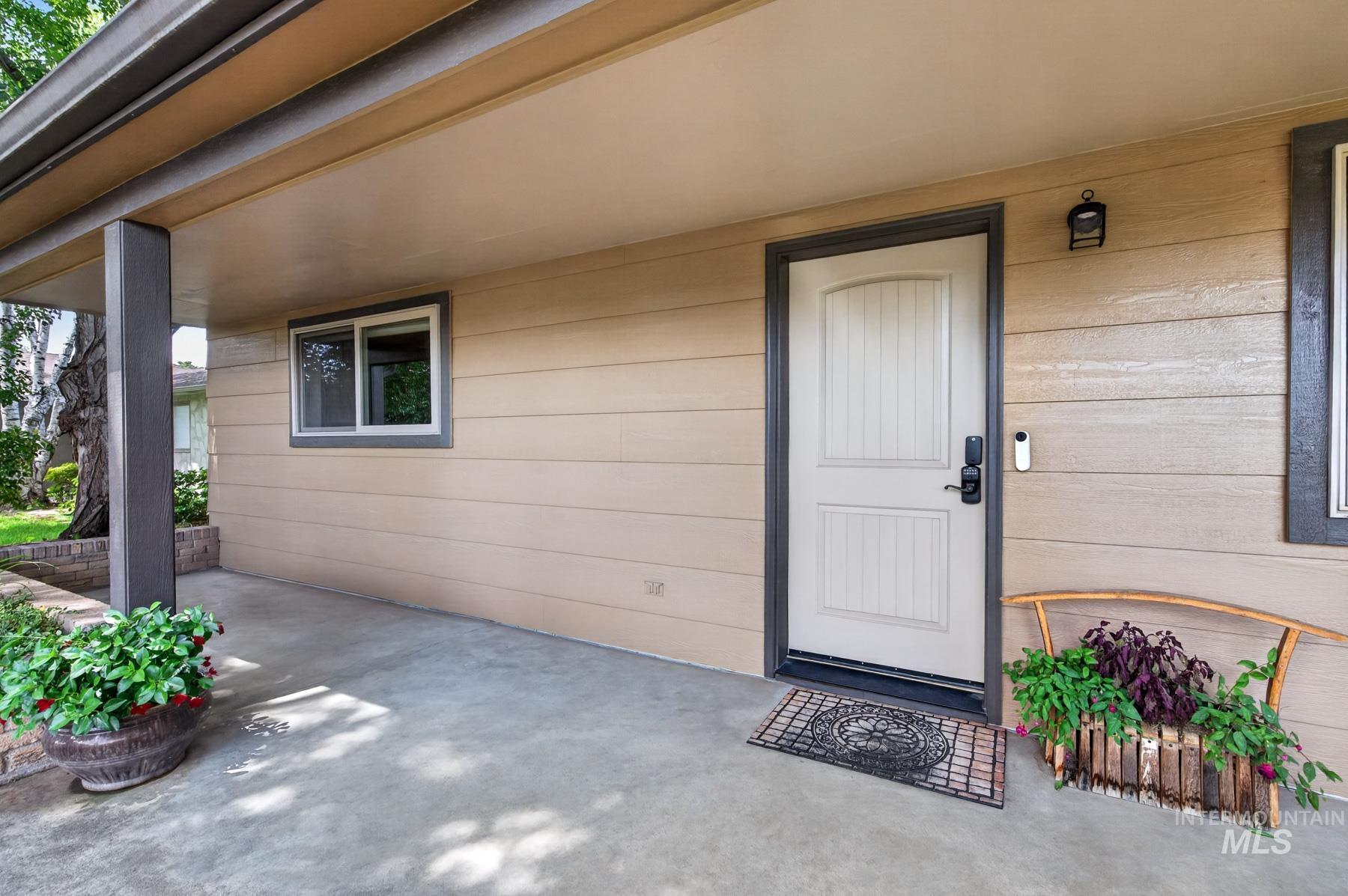 9622 Delaware Street Boise, ID 83709 - Photo 6 of 48 Covered entry porch featuring a paneled door with dark trim, horizontal siding, and an exterior light fixture
