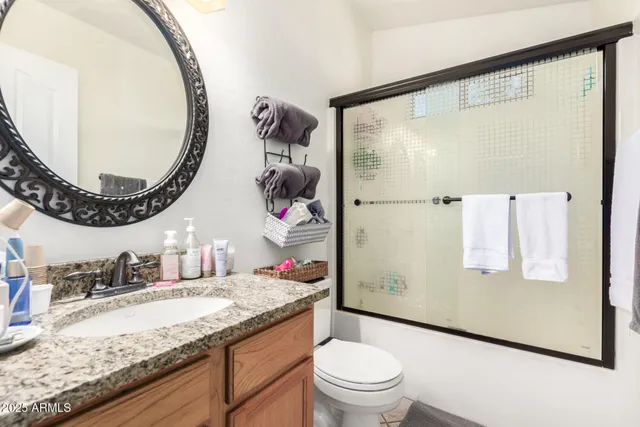 a bathroom with a granite countertop sink mirror vanity and toilet