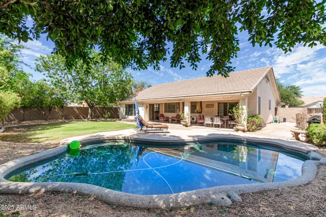 a view of house with swimming pool and yard