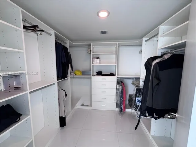 a view of walk in closet with clothes and shoes